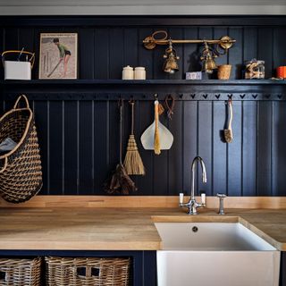 Dark blue kitchen with wall panelling and a long peg rail for kitchen utensils and cleaning equipment