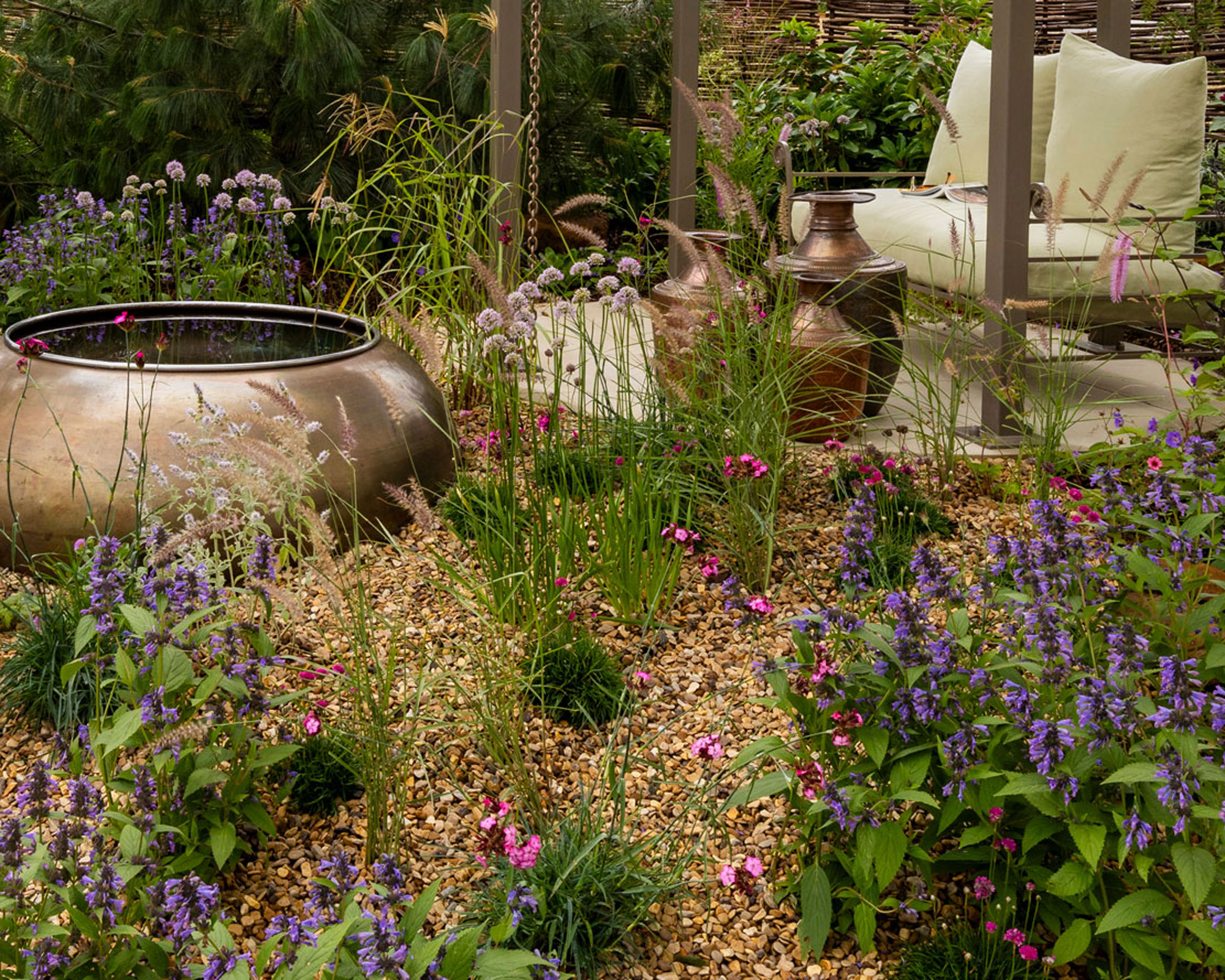 gravel landscaping with plants, water feature and garden sofa