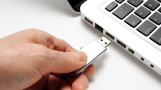 Someone connecting a USB Drive to their laptop.