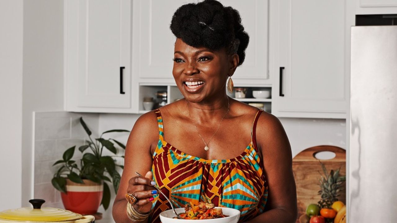 Yummy Spoonfuls founder Agatha Achindu smiling while holding a bowl of food she prepared.