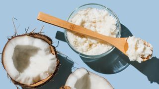 Glass bowl of coconut oil with half a whole coconut on either side