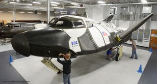 Technicians with the Sierra Nevada Corp. inspect the sub-orbital version of the Dream Chaser vehicle, which the company says would continue the legacy of NASA's shuttle program.