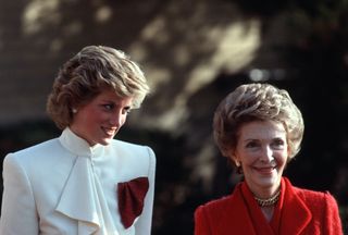 Diana, Princess of Wales, wearing a cream suit with a red scarf in the pocket, stands next to First Lady, Nancy Reagan, as they leave a drug rehabilitation centre on November 11, 1985 in Washington, DC