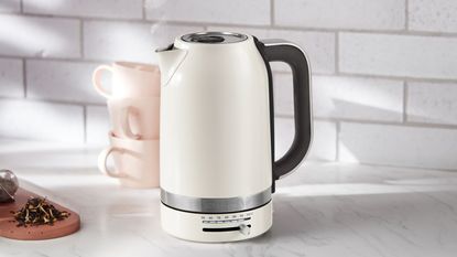 KitchenAid Electric Kettle in almond cream on a white countertop with two cups in the background