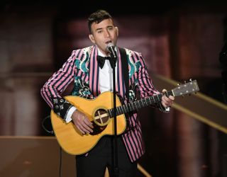 sufjan stevens performing in a pink striped suit at the oscars