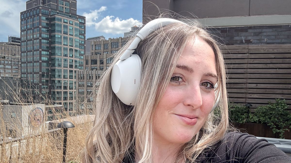 A woman wearing white Sony WH-1000XM6 noise-cancelling headphones