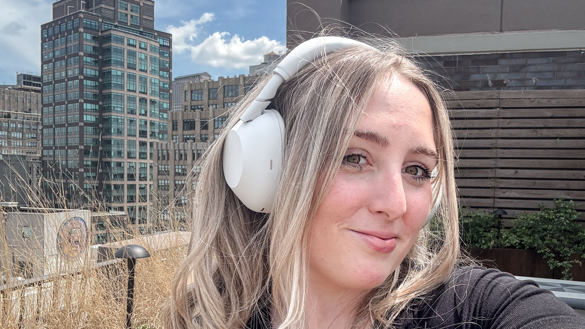 A woman wearing white Sony WH-1000XM6 noise-cancelling headphones