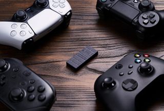 8bitdo wireless adapter 2 surrounded by xbox, ps5 and ps4 controllers