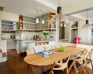 A white open plan kitchen with wooden table, chairs and pendant light.