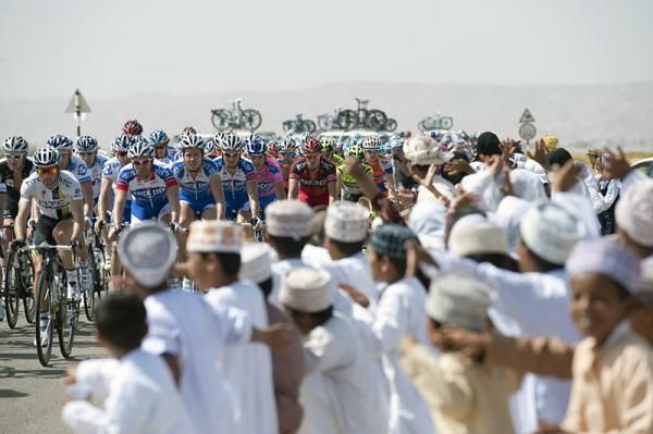 The Tour of Oman peloton passes through a pocket of spectators.