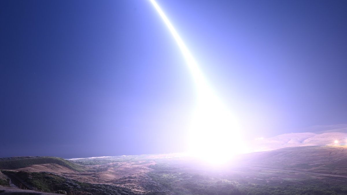 a bright streak of light arcs from the sky into the ocean