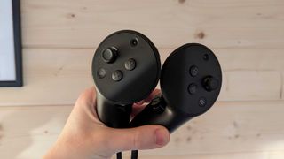 The Meta Quest Pro controllers being held by a person's hand