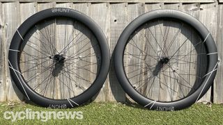 A pair of Hunt 60 Limitless Aero Disc wheels lean against a wooden fence