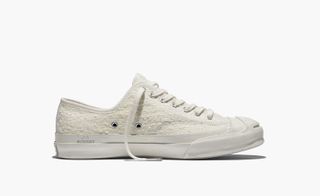 The side view of a white fabric sneaker with a white sole.