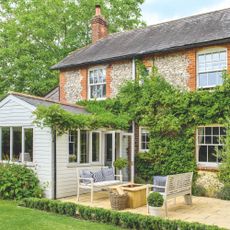 Large cottage with a patio area and garden furniture on it