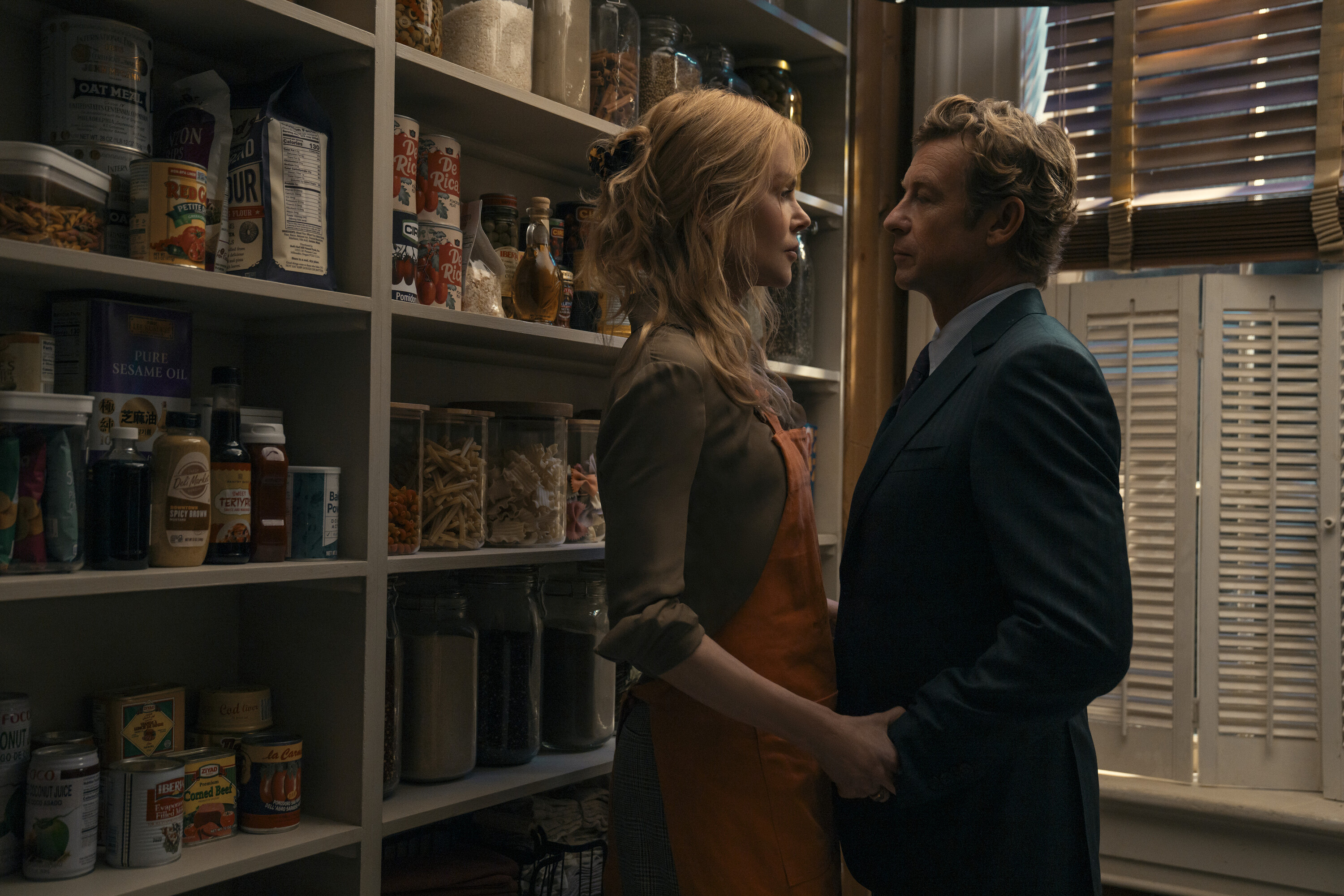 Kay Scarpetta (Nicole Kidman) and Benton Wesley (Simon Baker) embrace in a pantry with lots of dry food in a still from scarpetta