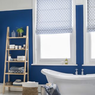 Blue bathroom with blue and white patterned roller blinds on windows