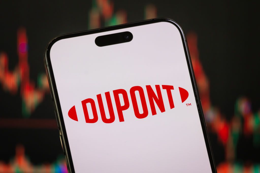 The DuPont logo featured on a smartphone with a blurred stock chart in the background