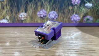 Nagaoka MP-200 moving magnet cartridge on wooden table in front of flower picture showing pins