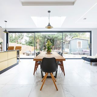 Modern open-plan kitchen diner with floor-to-ceiling glass sliding doors leading to garden