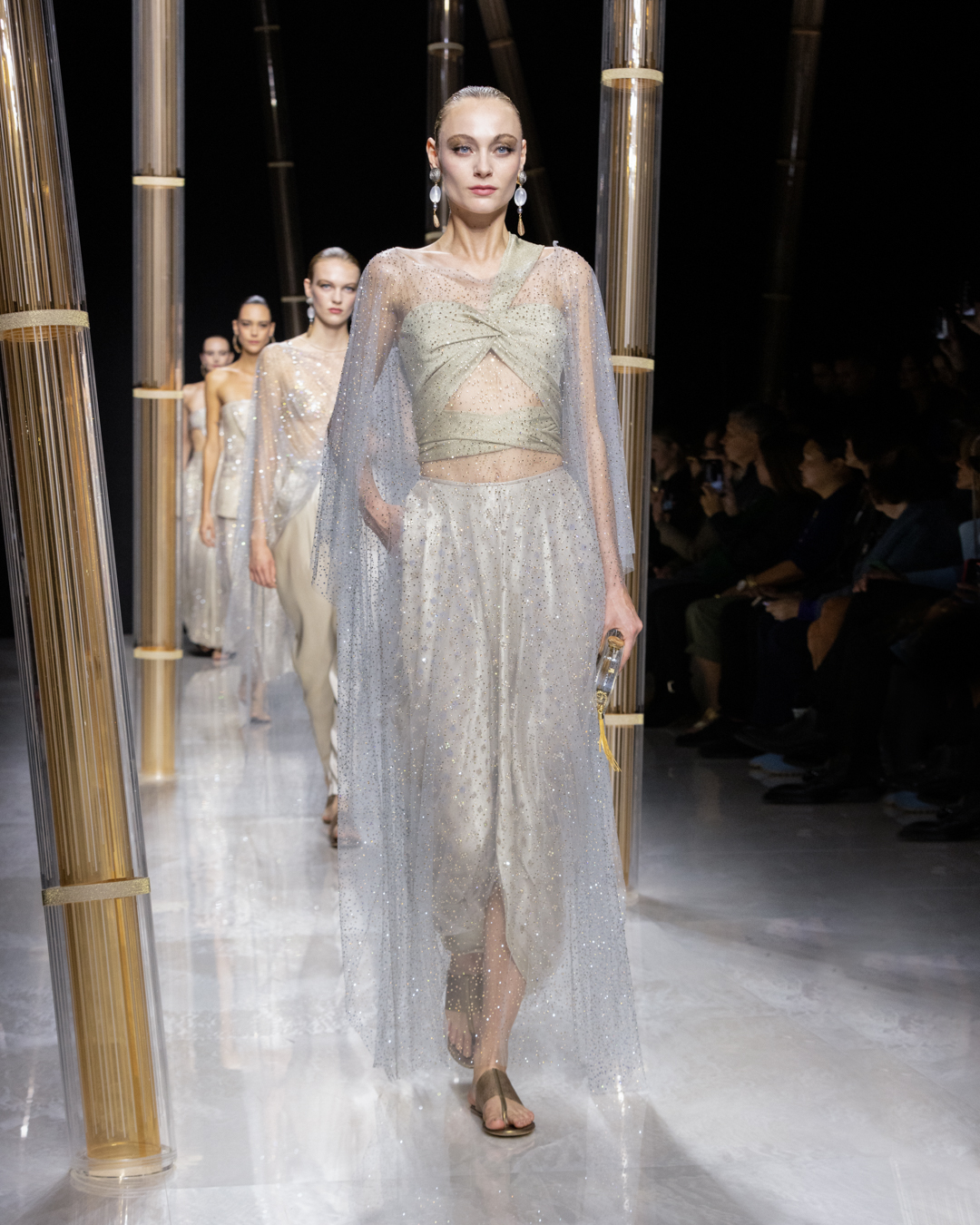 Female models walking down a runway wearing various types of white lace dresses.