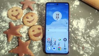 The Moto G84's home screen next to some festive cookies