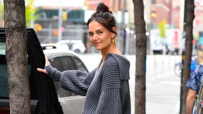 Katie Holmes in a gray sweater and gold pants