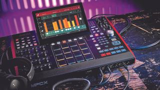Shot of an Akai MPC X on a black wooden bench in a venue with a pair of headphones resting on it 