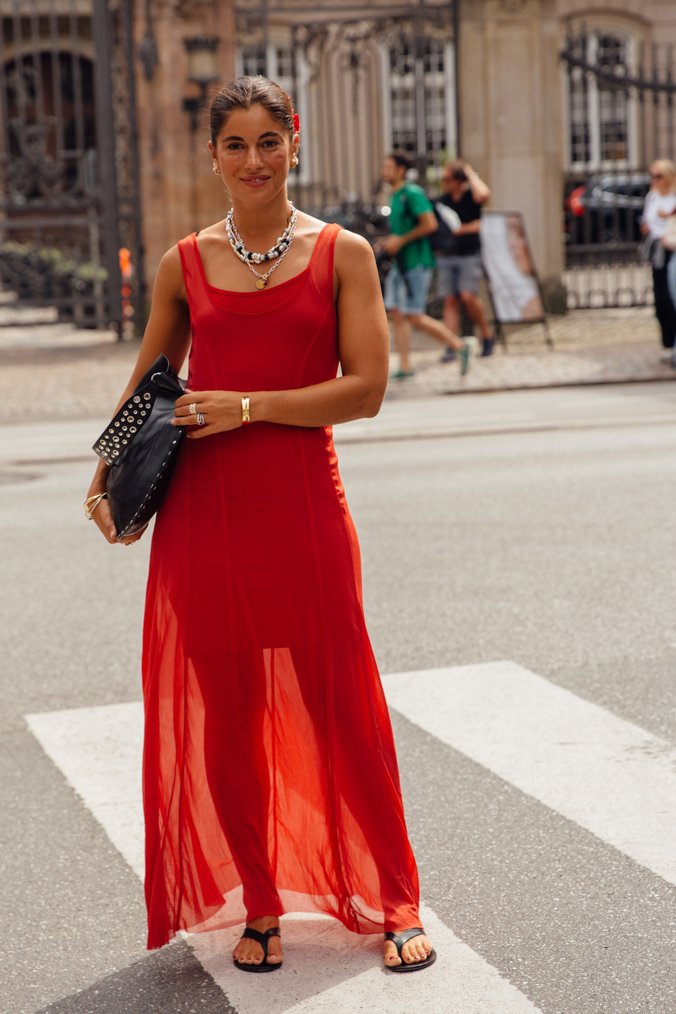 a woman wearing a red dress and black flip flops at fashion week