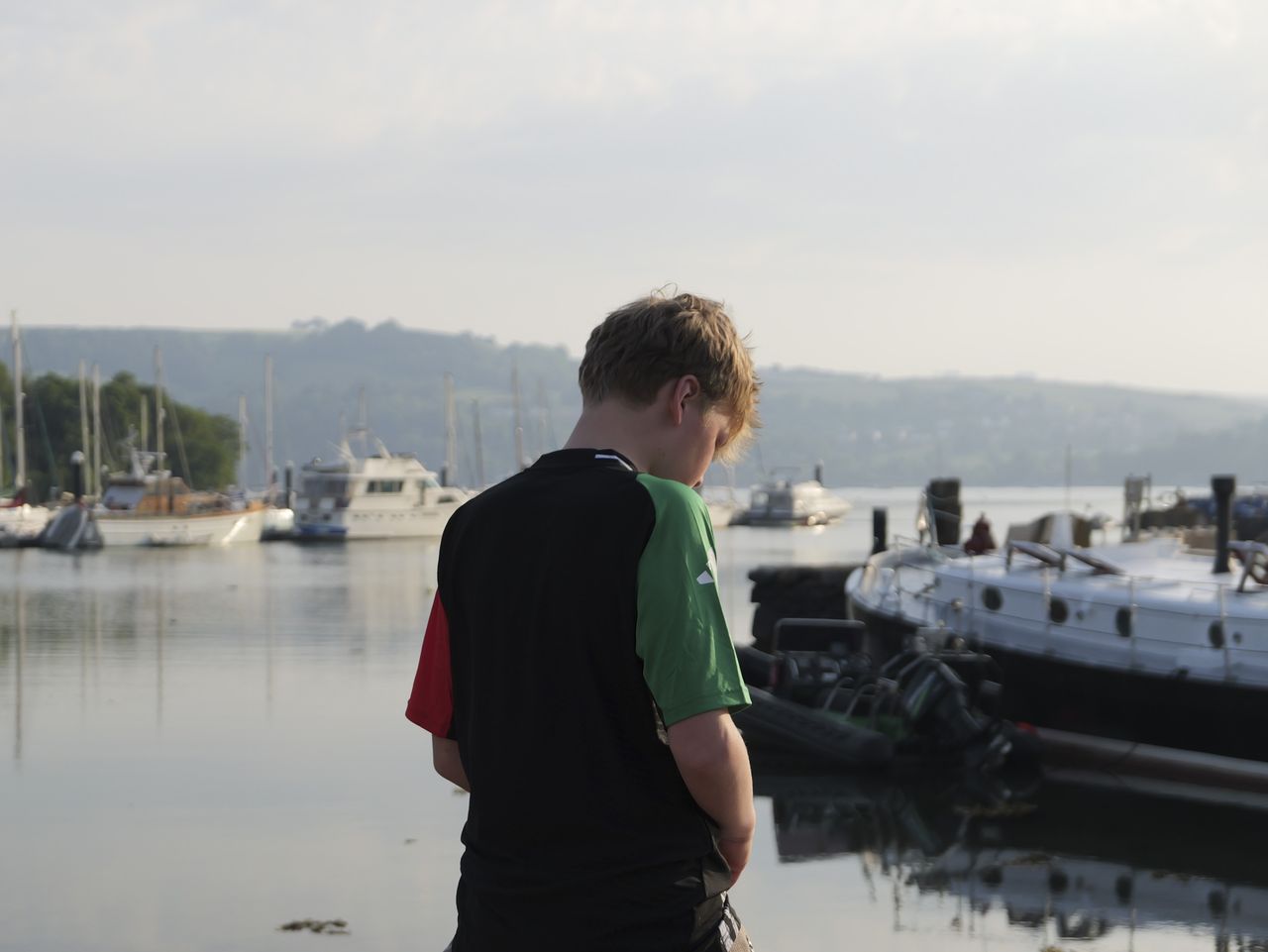 Sample image taken with the Panasonic Lumix L10; back of a teenage boy, stood by a lake with boats