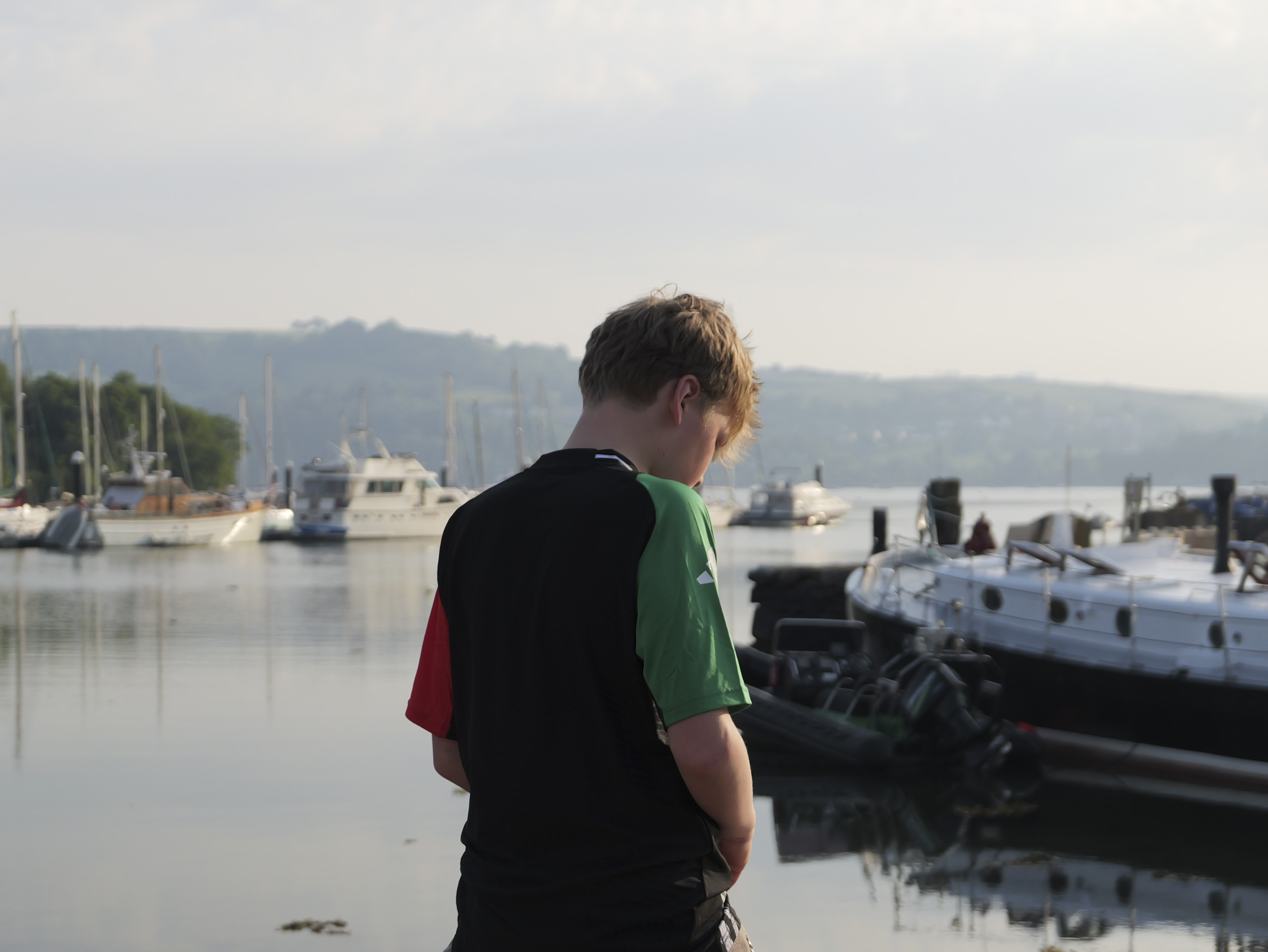 Sample image taken with the Panasonic Lumix L10; back of a teenage boy, stood by a lake with boats