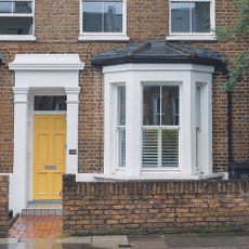 Victorian terraced house with yellow front door next to bay window.