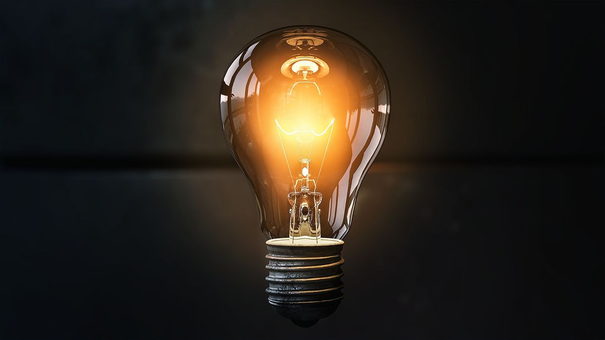 A lightbulb glowing softly against a black backdrop.