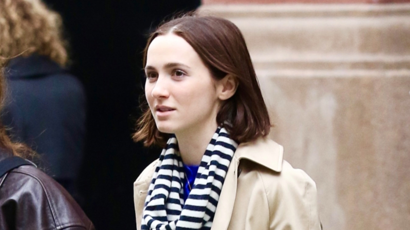 Maude Apatow wearing a trench coat and striped scarf