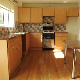 dated kitchen with pine cabinets and colourful tiles