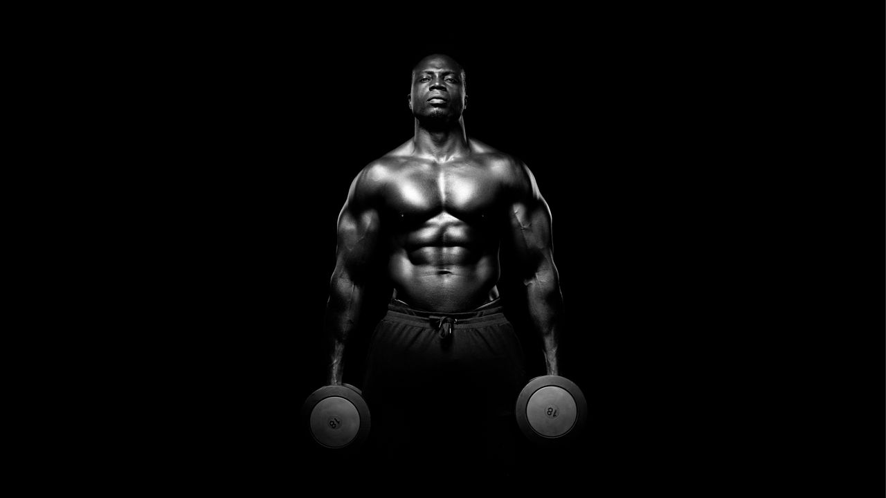 Muscular person holdiong dumbbells in his hands