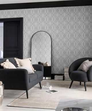 A black and grey living room with grey and white peel-and-stick wallpaper wallcovering decor, upholstered sofa and black framed floor-length mirror