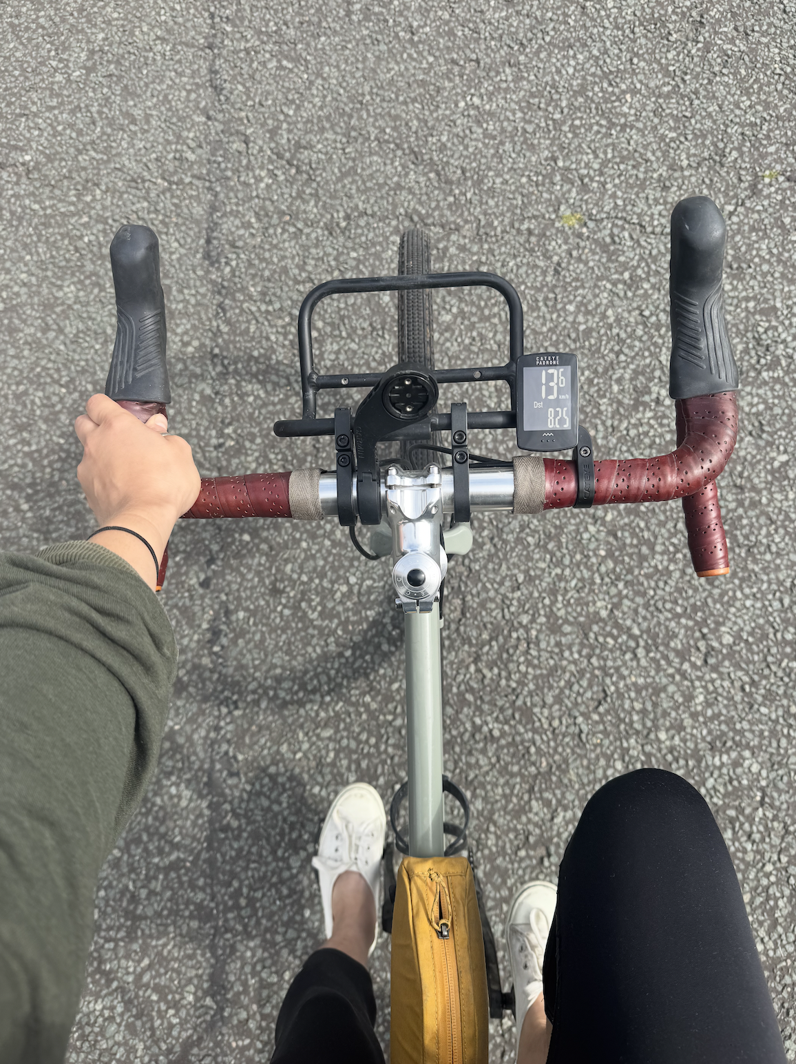The Cateye Padrone sits on the handlebars of a bike next to a front rack. It's display is on and shows Km/h and distance