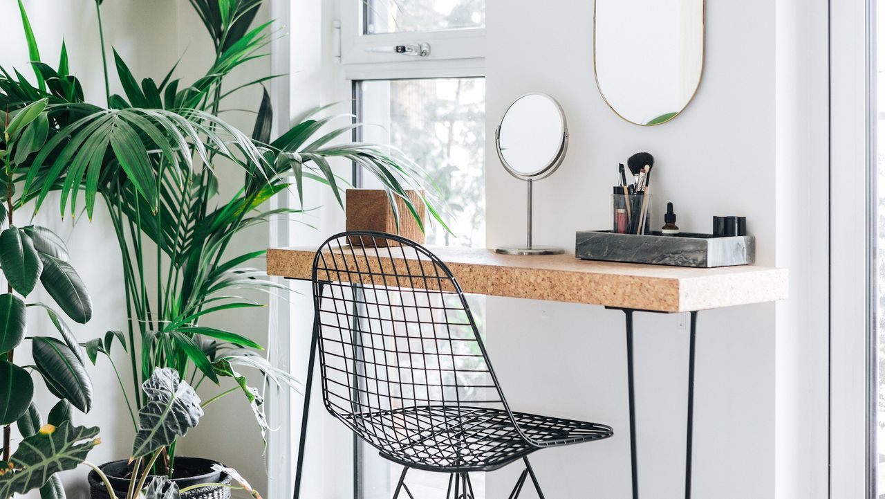 An industrial wood and black metal hairpin leg vanity with a nearby plant up against a white wall with mirrors