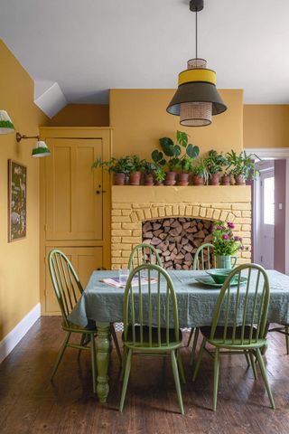 A yellow dining room with a large painted brick fireplace