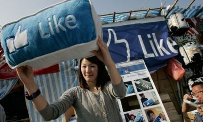 A woman displays a Facebook cushion on sale in China