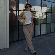 Alyssa wears white open back top, men's trousers, light green handbag, sunglasses, and earrings