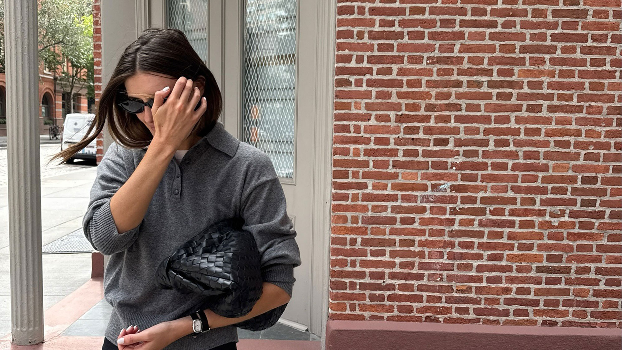 Woman wearing a gray polo sweater.