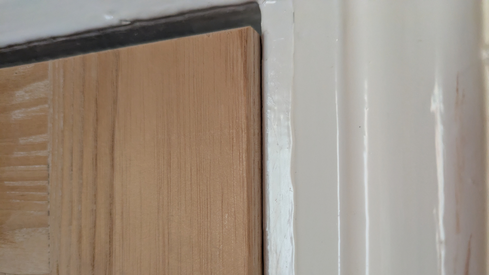 Detail photo of a sagging door which is rubbing against the door frame