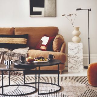 A bright living room with a brown sofa and a set of black nesting coffee tables