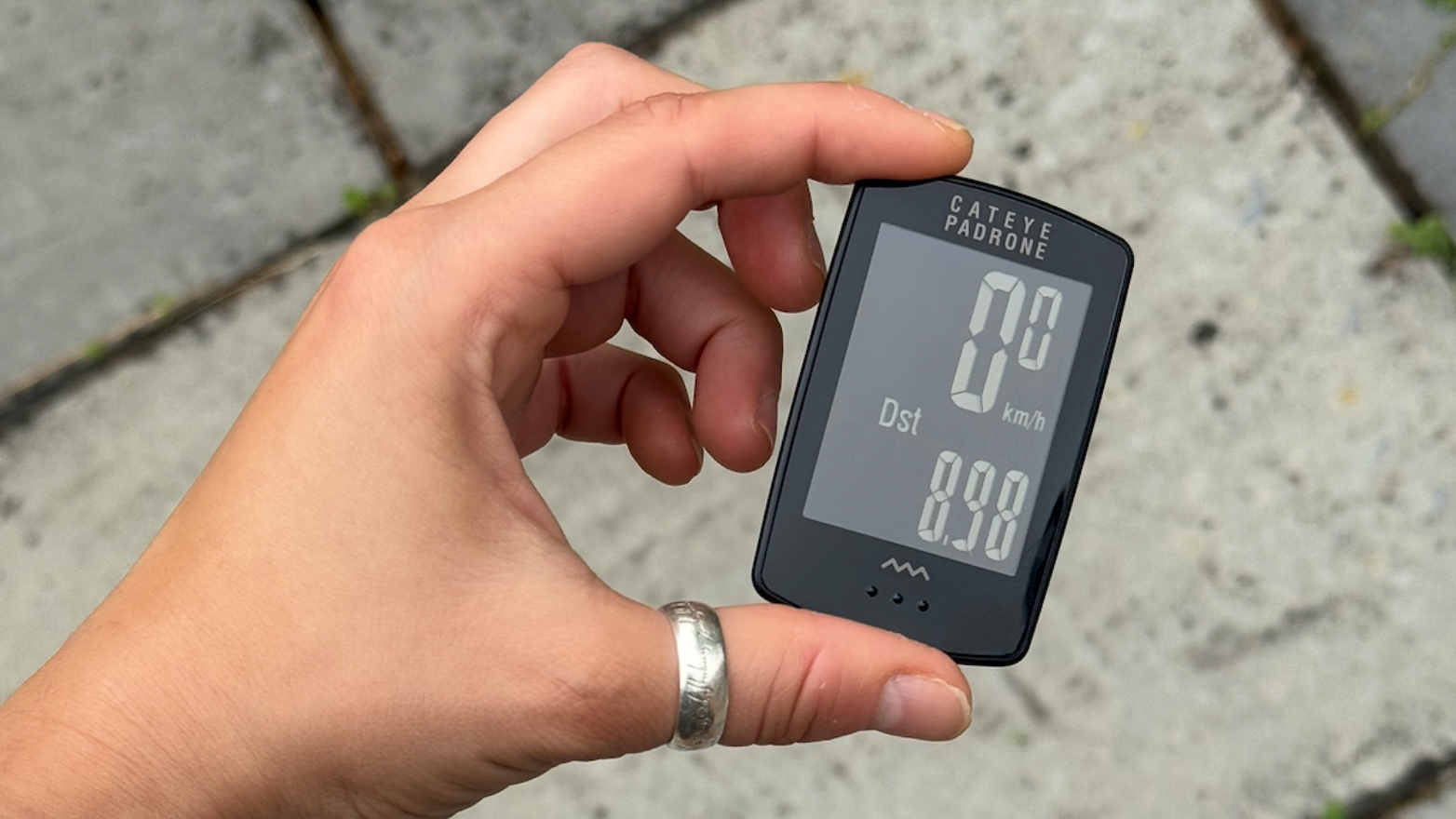 The Cateye Padrone being held in hand, showing size of the device and the screen details 