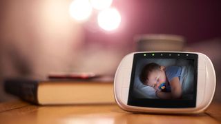 Best baby camera monitors - monitor on bedside table with image of baby sleeping on it