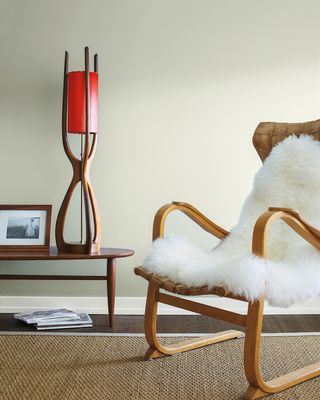 White dove white paint color used in a living room with modern wooden frame chair styled with white sheepskin rug
