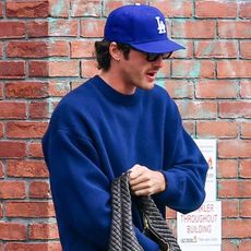10/20/2025: Jacob Elordi is spotted carrying a large Bottega Veneta handbag in New York City. The American actor wore a blue cap, matching cropped sweatshirt, jeans, and red Nike trainers.
