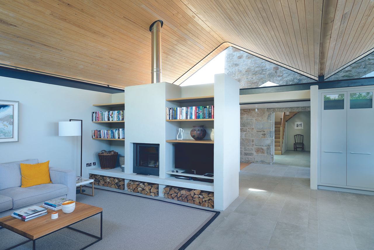 woodburning stove surrounded by white bookshelf in cottage extension